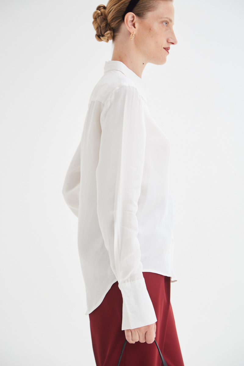 Camisa blanca de calce recto y puños anchos con textura suave de piel de durazno. 
