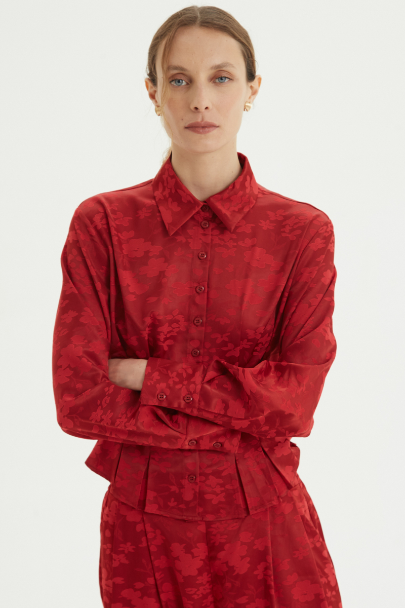 Camisa roja satinada de jacquard floreado con pinzas de entalle en frente y espalda, con lazo para regular. 