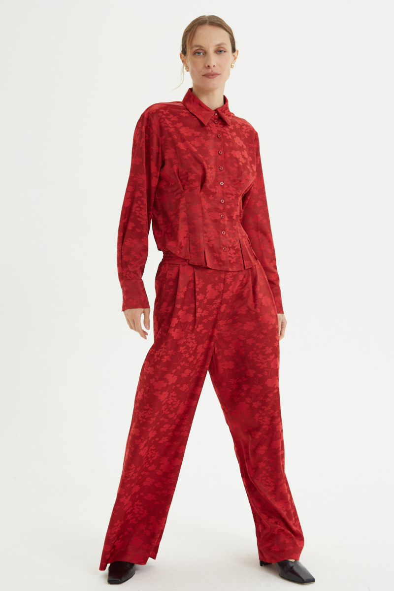 Camisa roja satinada de jacquard floreado con pinzas de entalle en frente y espalda, con lazo para regular. 