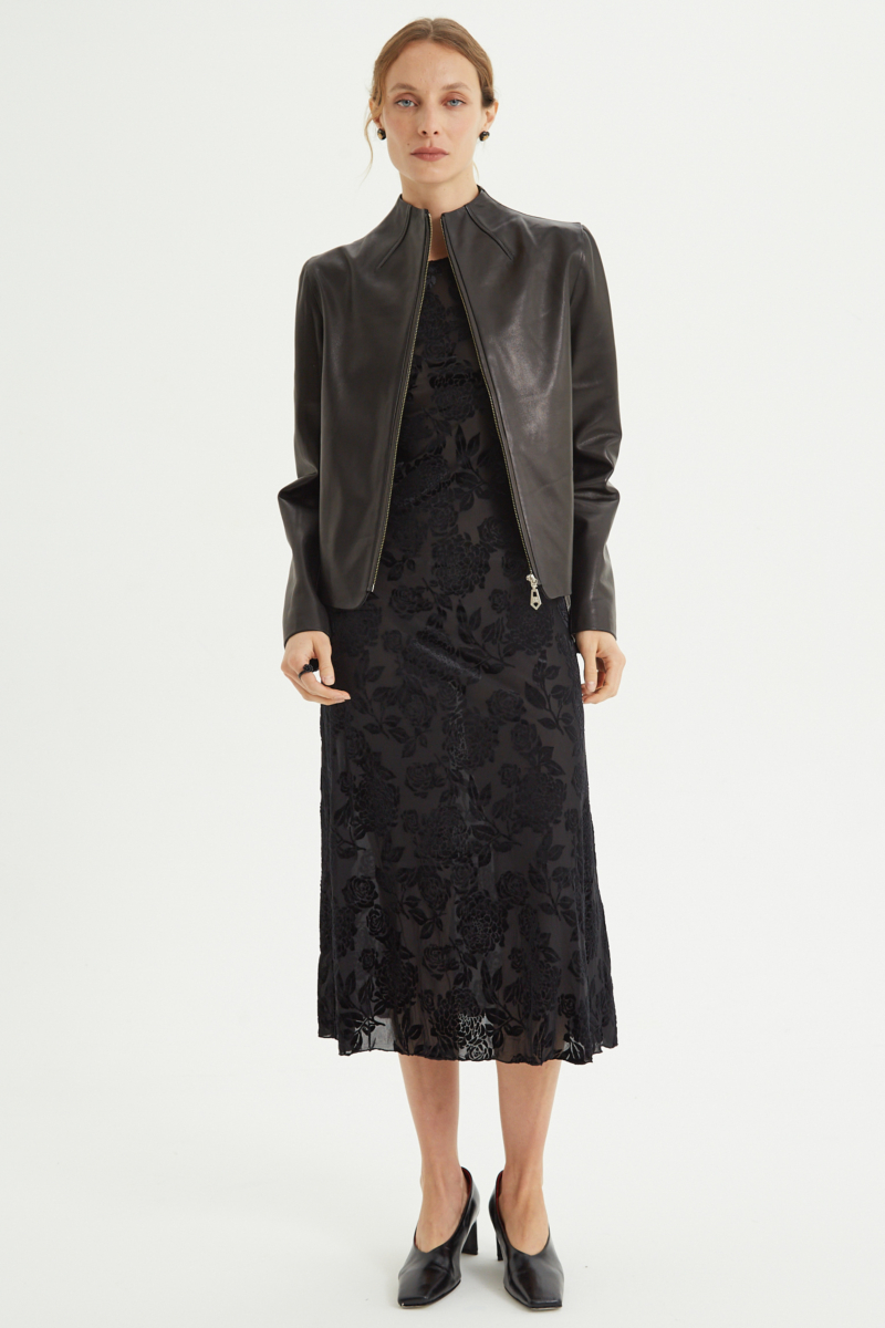 Vestido negro largo y al cuerpo de microtul con textura de flores de terciopelo y cuello bote. 