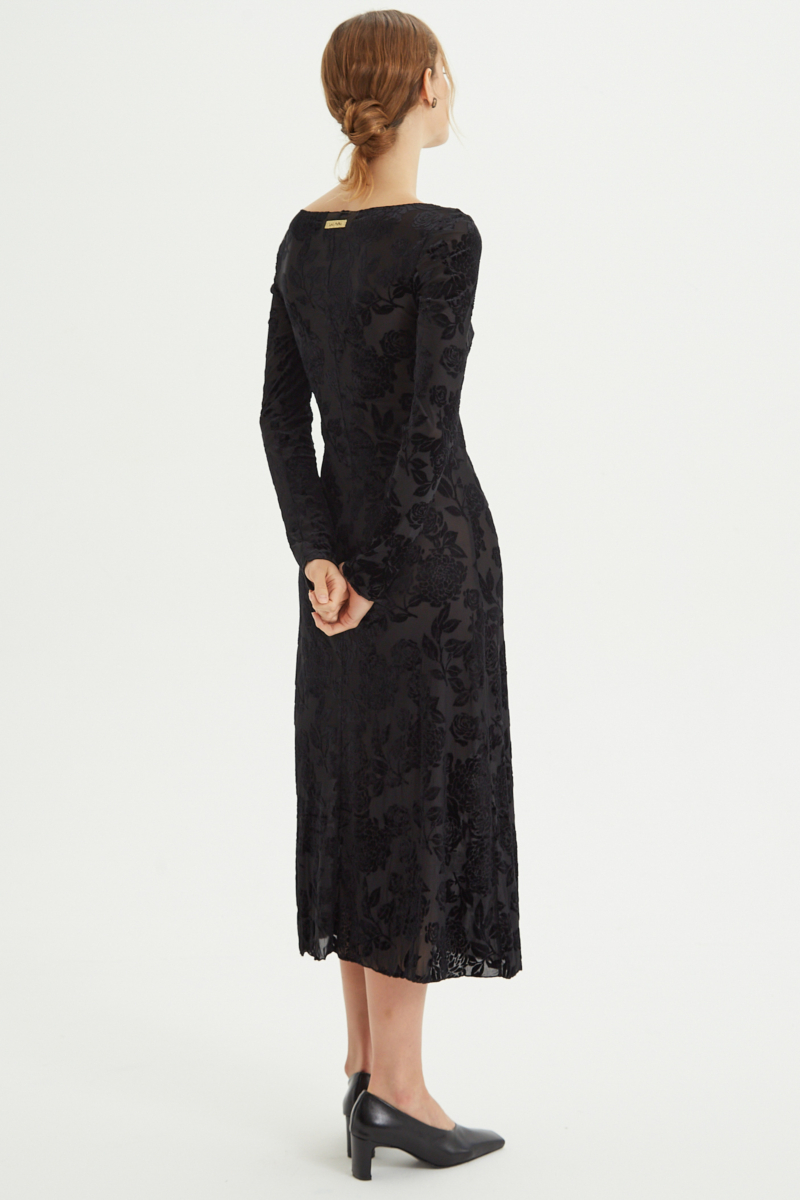 Vestido negro largo y al cuerpo de microtul con textura de flores de terciopelo y cuello bote. 