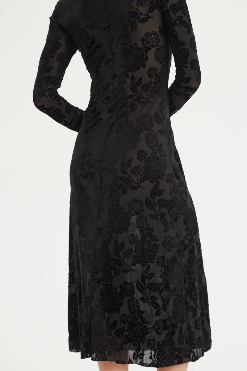 Vestido negro largo y al cuerpo de microtul con textura de flores de terciopelo y cuello bote. 