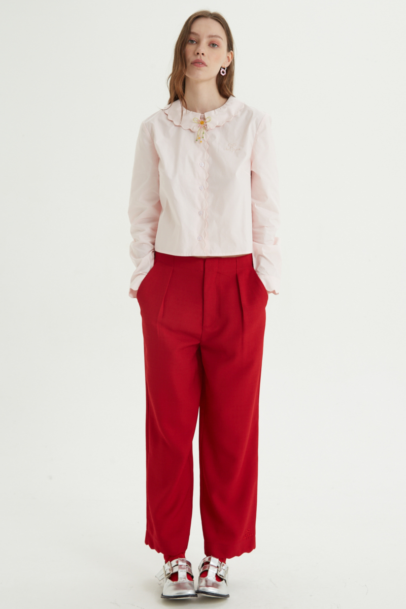 Camisa rosa de poplin de largo hasta la cadera con terminación en forma de onditas en cuello, puños y cartera y botones a tono en forma de flor. 