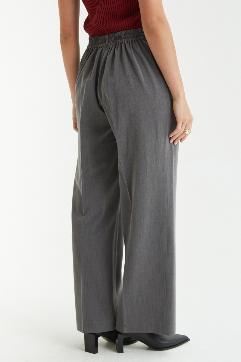 Pantalón gris sastrero tiro alto y recto con herrajes metálicos, pliegue en las piernas y elástico en la cintura trasera. 
