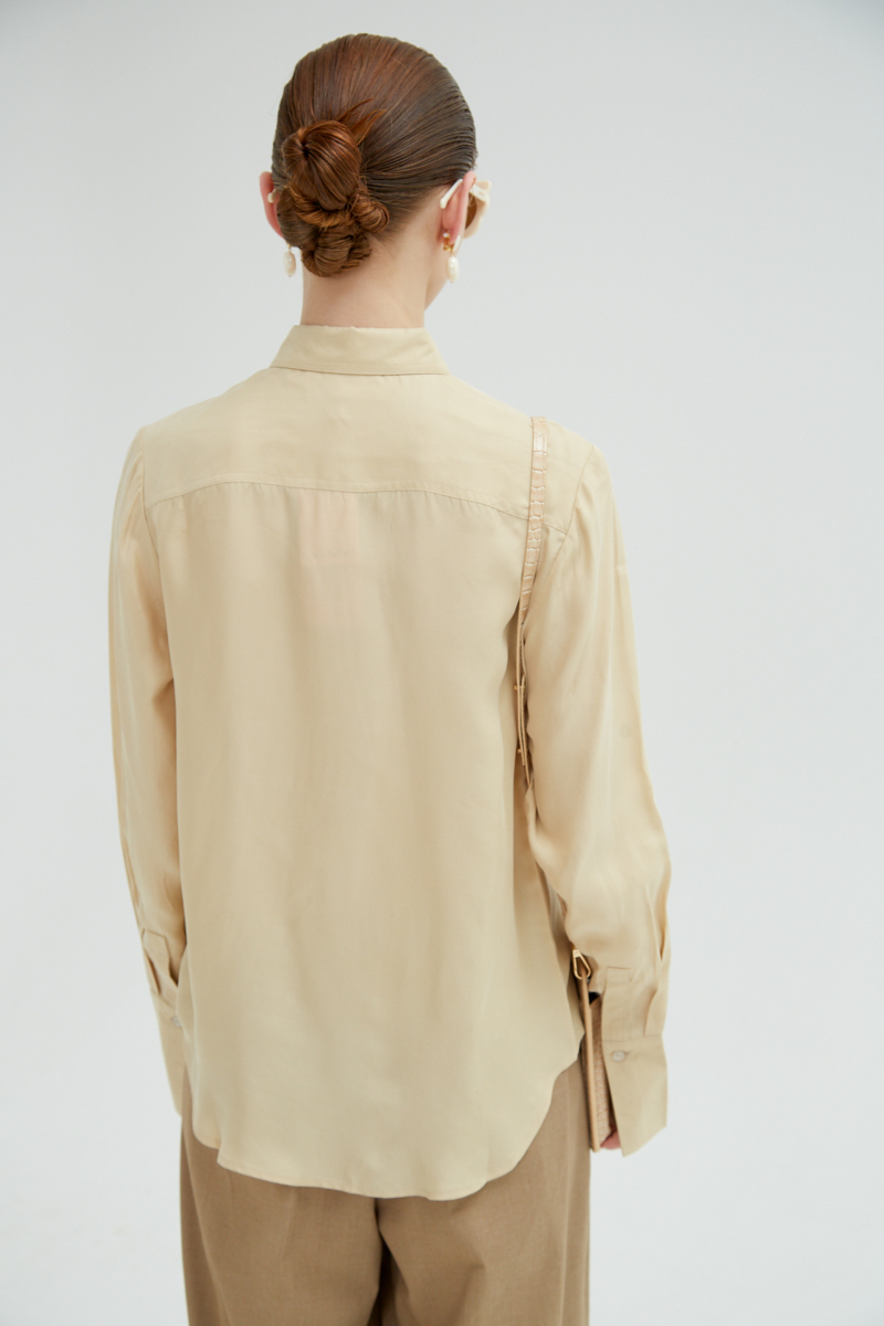 Camisa beige de calce recto y puños anchos con textura suave de piel de durazno. 
