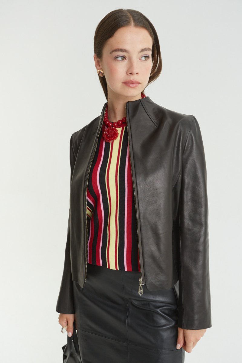 Campera de cuero negro con cuello alto y cierre metálico, de calce recto y larga hasta la cadera.
