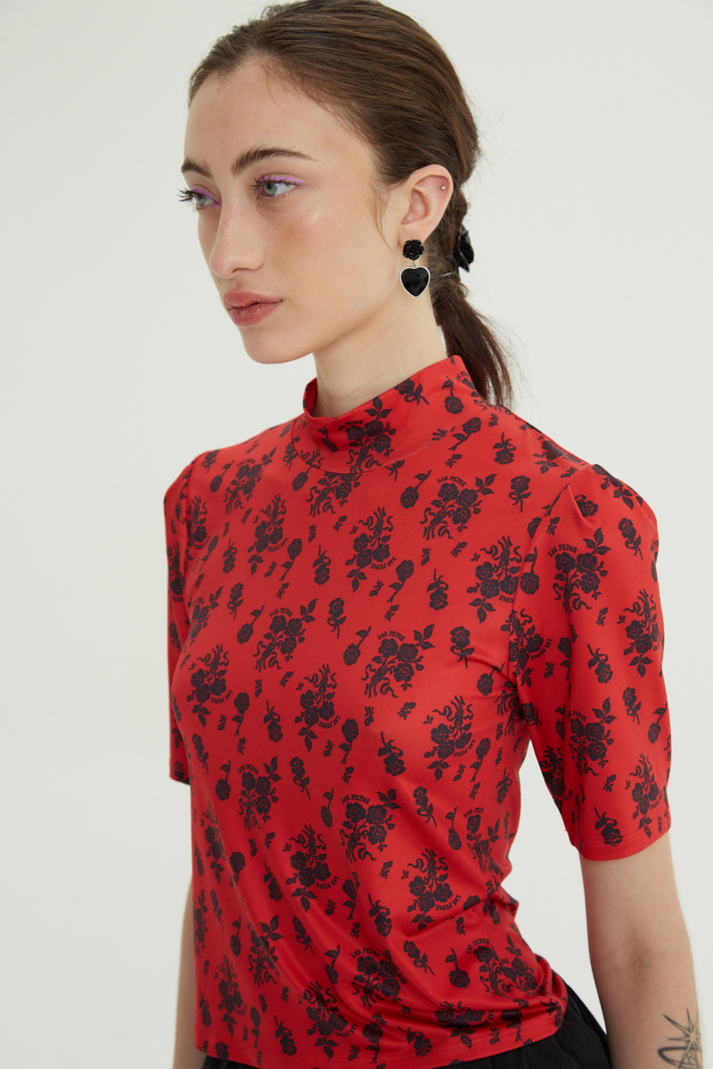 Remera roja entallada y larga a la cadera con cuello semi polera y mangas ¾ con frunces, estampada con print de rosas. 