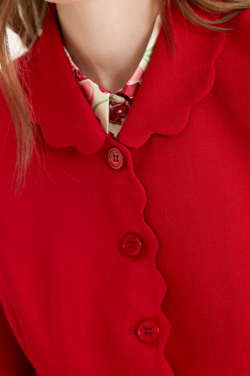 Blazer rojo sastrero entallado con terminación ondulada y mangas princesa. 
