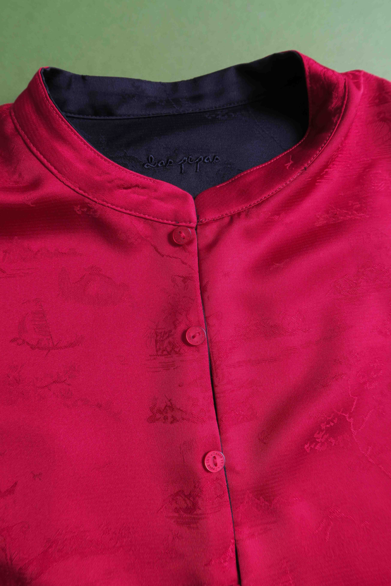 Blusa negra reversible de jacquard satinado sin mangas con cuello mao, botones a tono, pinzas frontales y aberturas laterales.
