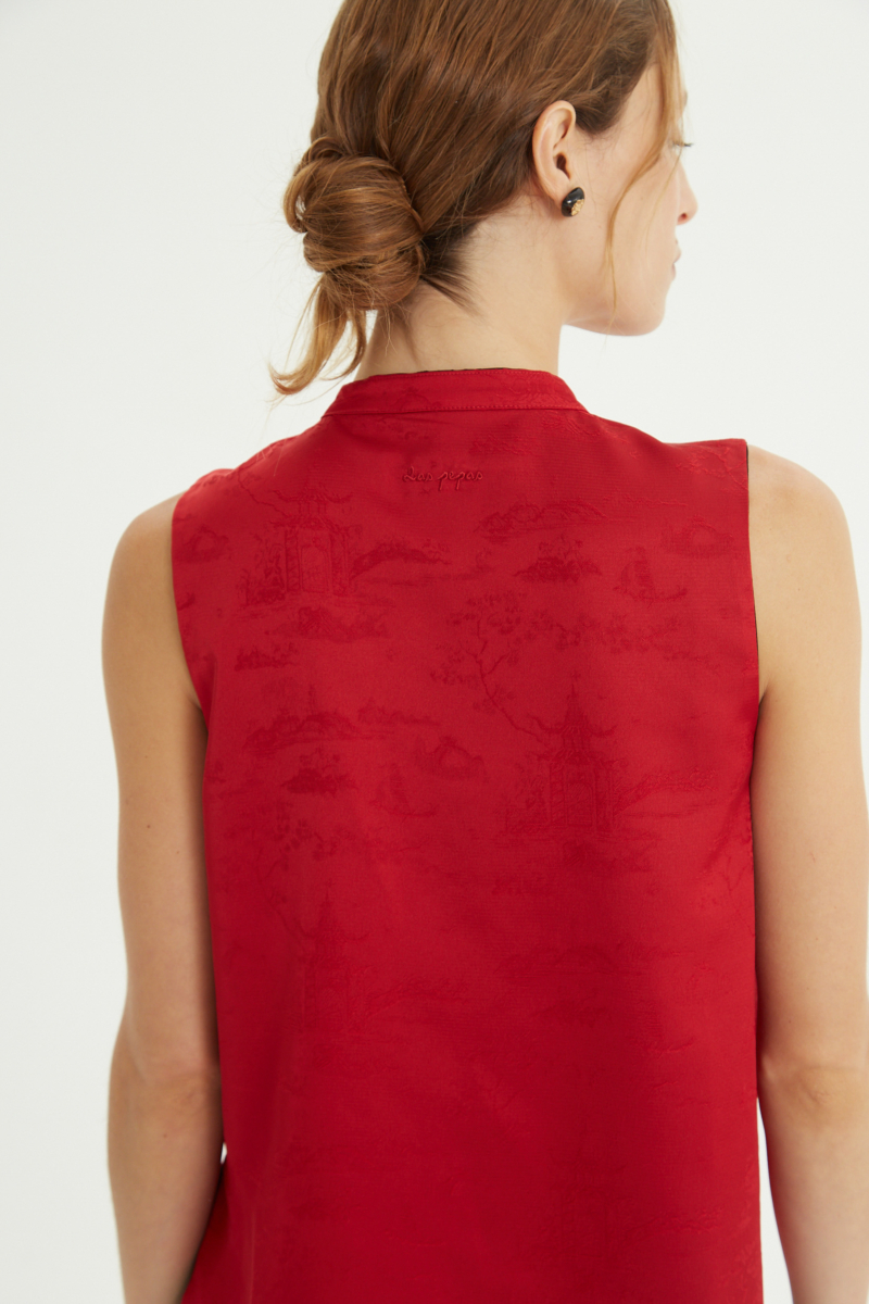 Blusa negra reversible de jacquard satinado sin mangas con cuello mao, botones a tono, pinzas frontales y aberturas laterales.