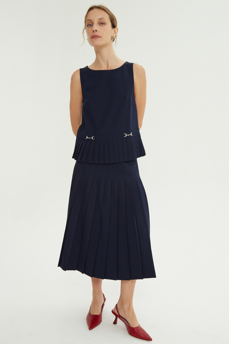 Blusa azul sastrera sin mangas con tablas en la cintura, herrajes metálicos y escote a la base del cuello, larga a la cadera. 