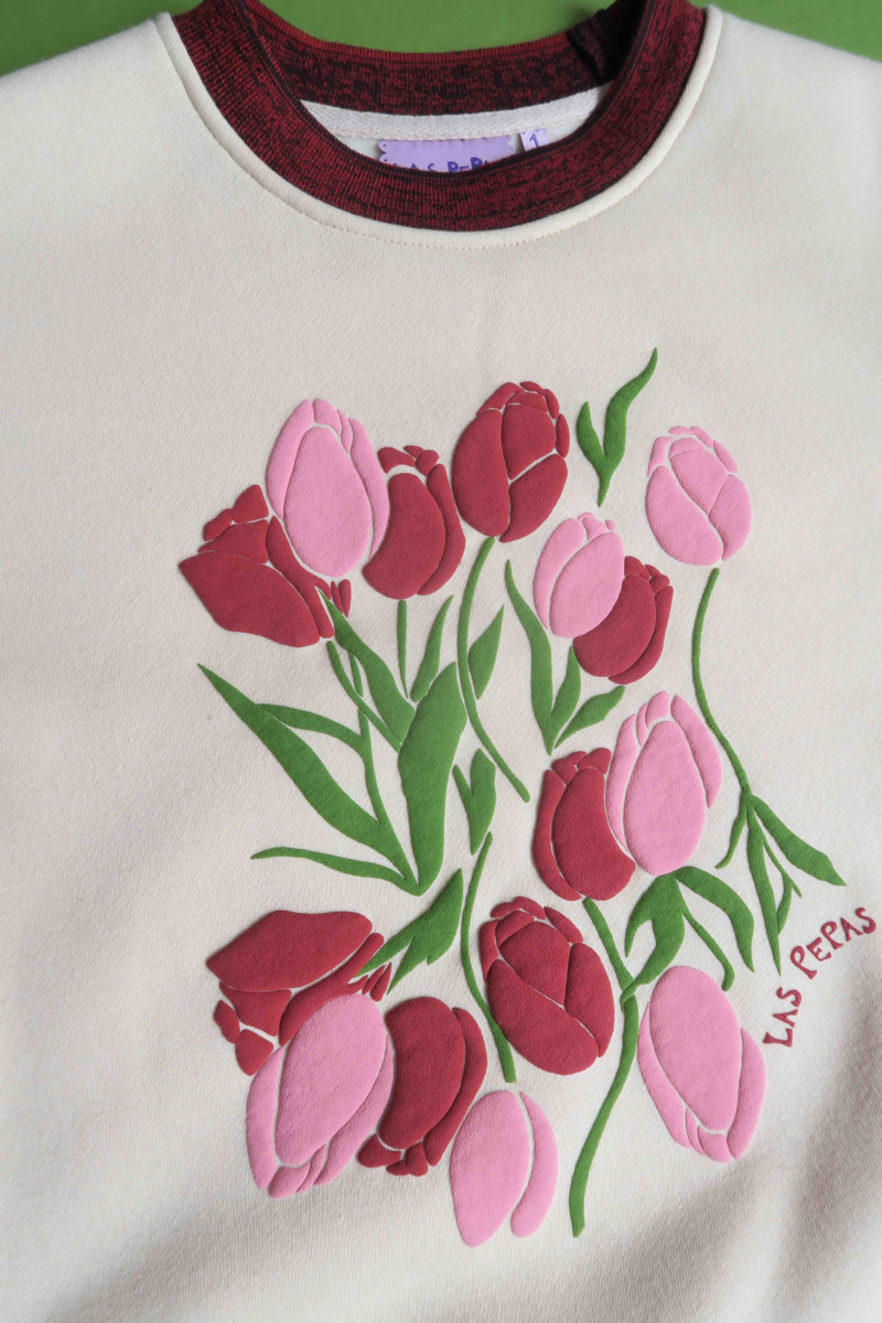 Buzo con estampa de tulipanes en relieve, recto y largo a la cadera con hombros caídos y terminaciones de rib jaspeado a contratono en cuello, puños y ruedo.