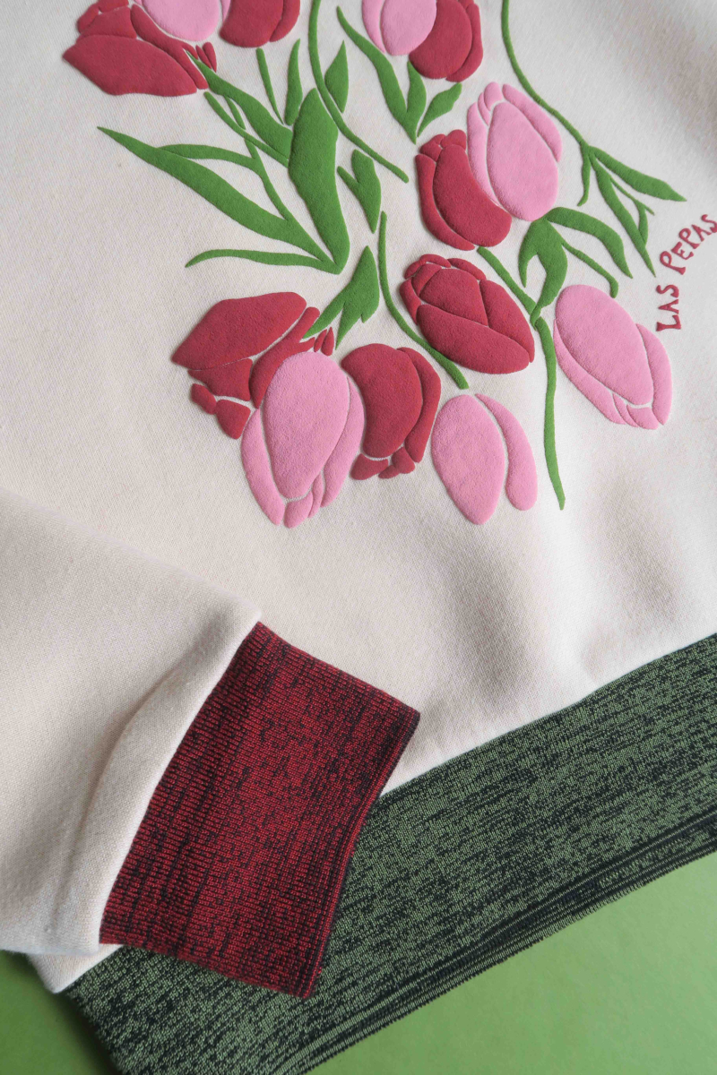 Buzo con estampa de tulipanes en relieve, recto y largo a la cadera con hombros caídos y terminaciones de rib jaspeado a contratono en cuello, puños y ruedo.