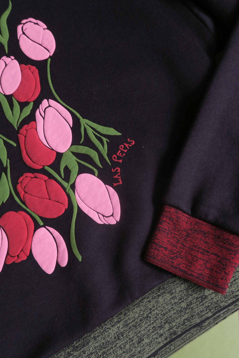 Buzo con estampa de tulipanes en relieve, recto y largo a la cadera con hombros caídos y terminaciones de rib jaspeado a contratono en cuello, puños y ruedo.