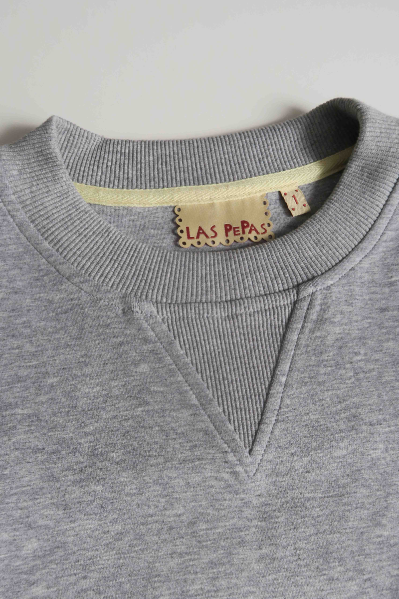 Buzo gris de algodón con mangas amplias, cuello redondo, hombros y sisas caídas. 
