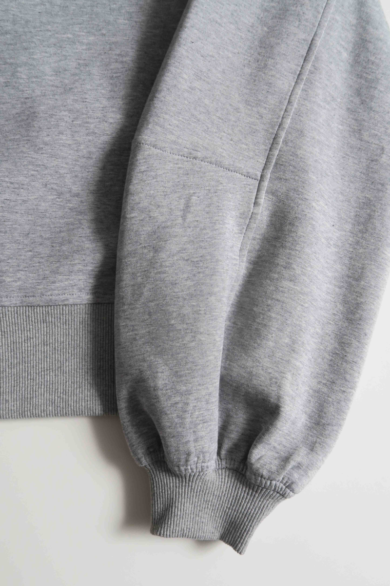 Buzo gris de algodón con mangas amplias, cuello redondo, hombros y sisas caídas. 
