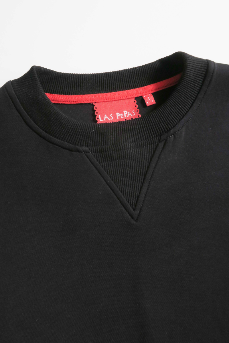 Buzo negro de algodón con mangas amplias, cuello redondo, hombros y sisas caídas. 
