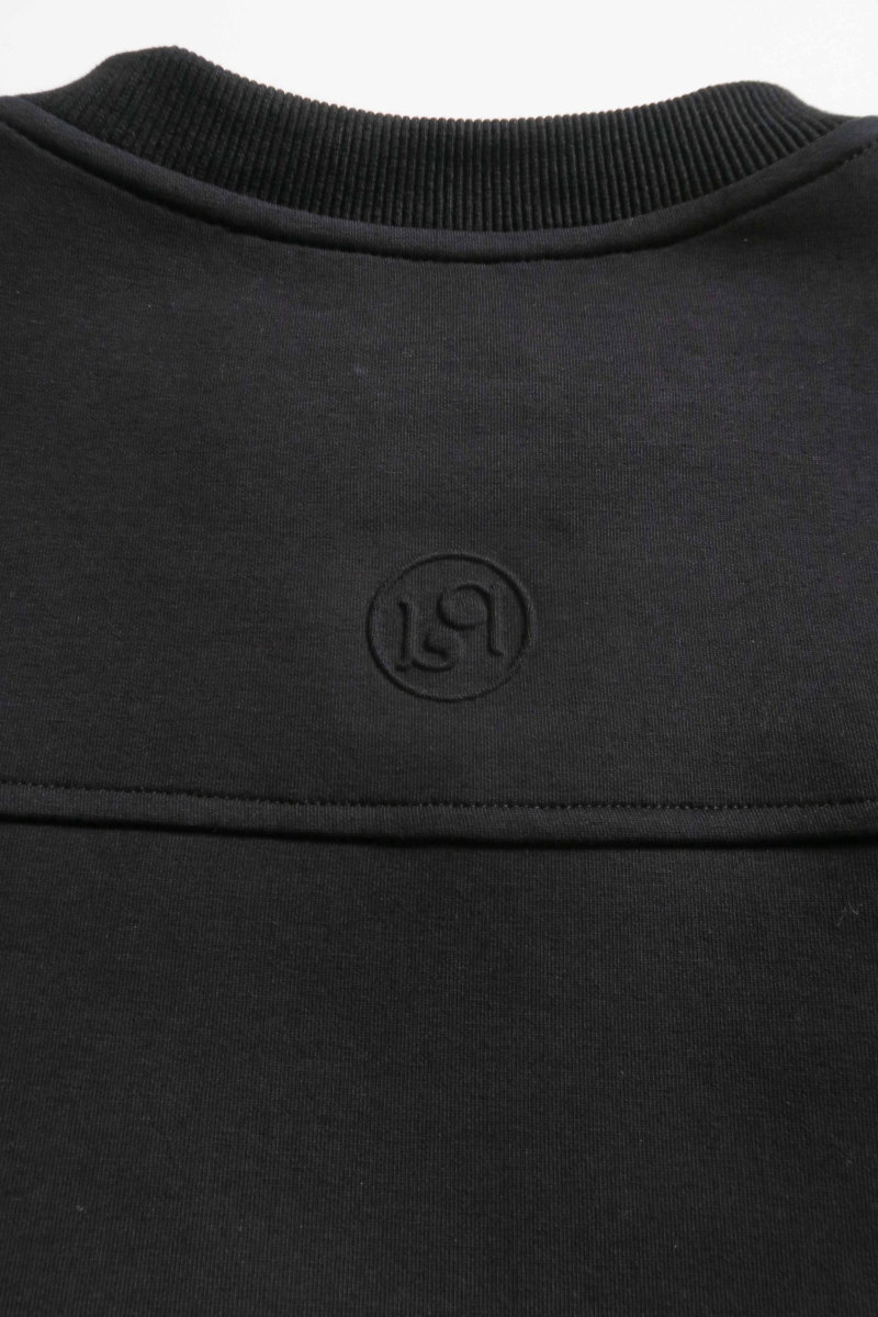 Buzo negro de algodón con mangas amplias, cuello redondo, hombros y sisas caídas. 
