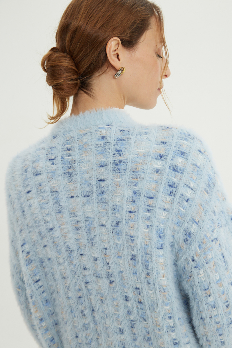 Saco tejido multicolor con textura de pelo y botones perlados en forma de flor. 
