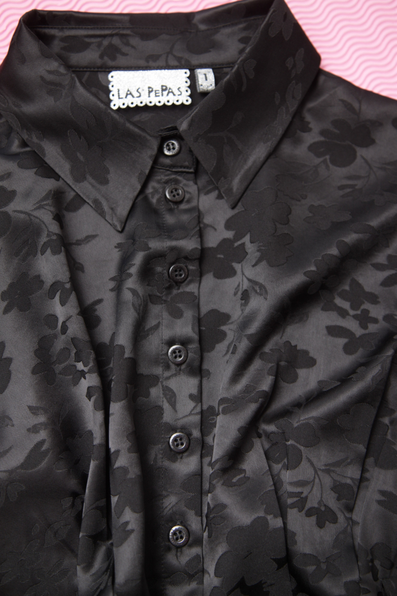 Camisa negra satinada de jacquard floreado con pinzas de entalle en frente y espalda, con lazo para regular. 
