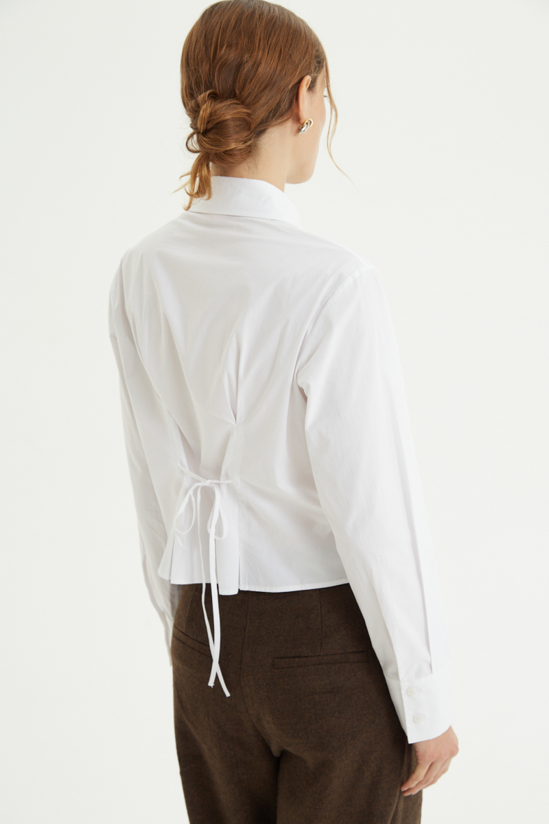 Camisa blanca entallada de poplín de algodón con pinzas de entalle frontales y en la espalda y lazo para ajustar. 
