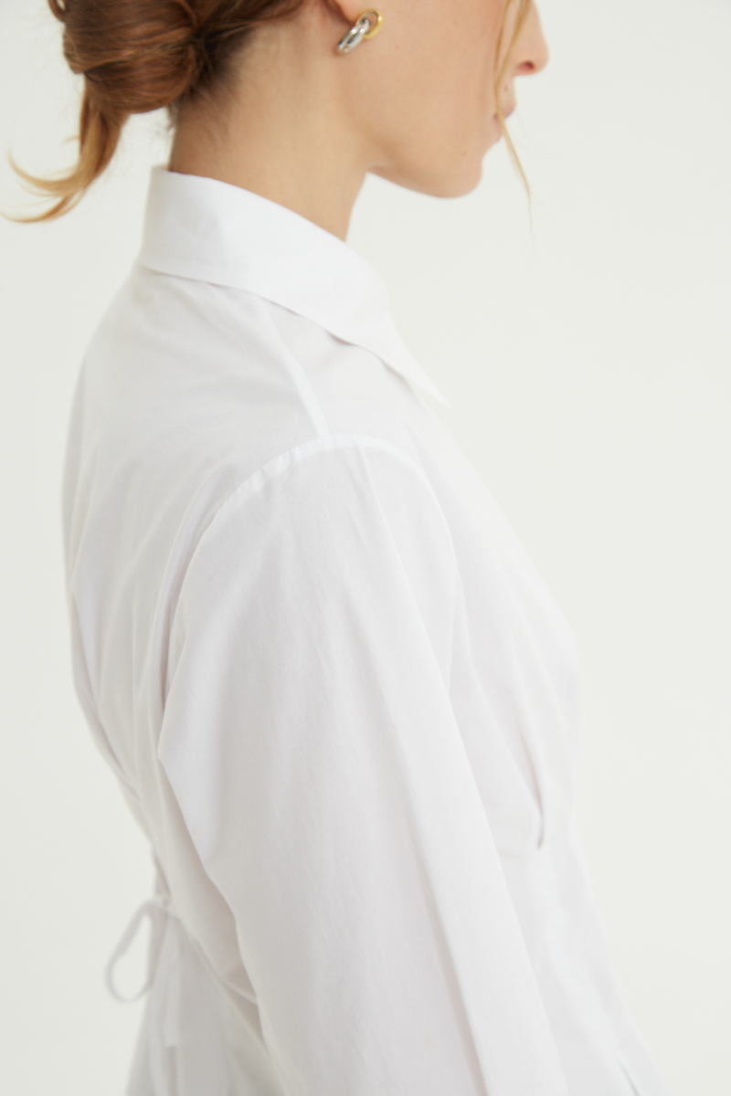 Camisa blanca entallada de poplín de algodón con pinzas de entalle frontales y en la espalda y lazo para ajustar. 
