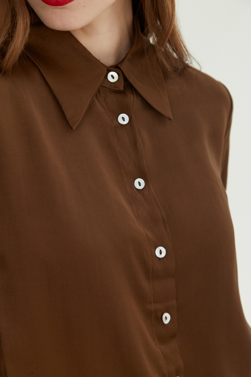 Camisa satinada con botones nacarados a contratono, de corte recto y larga hasta la cadera. 