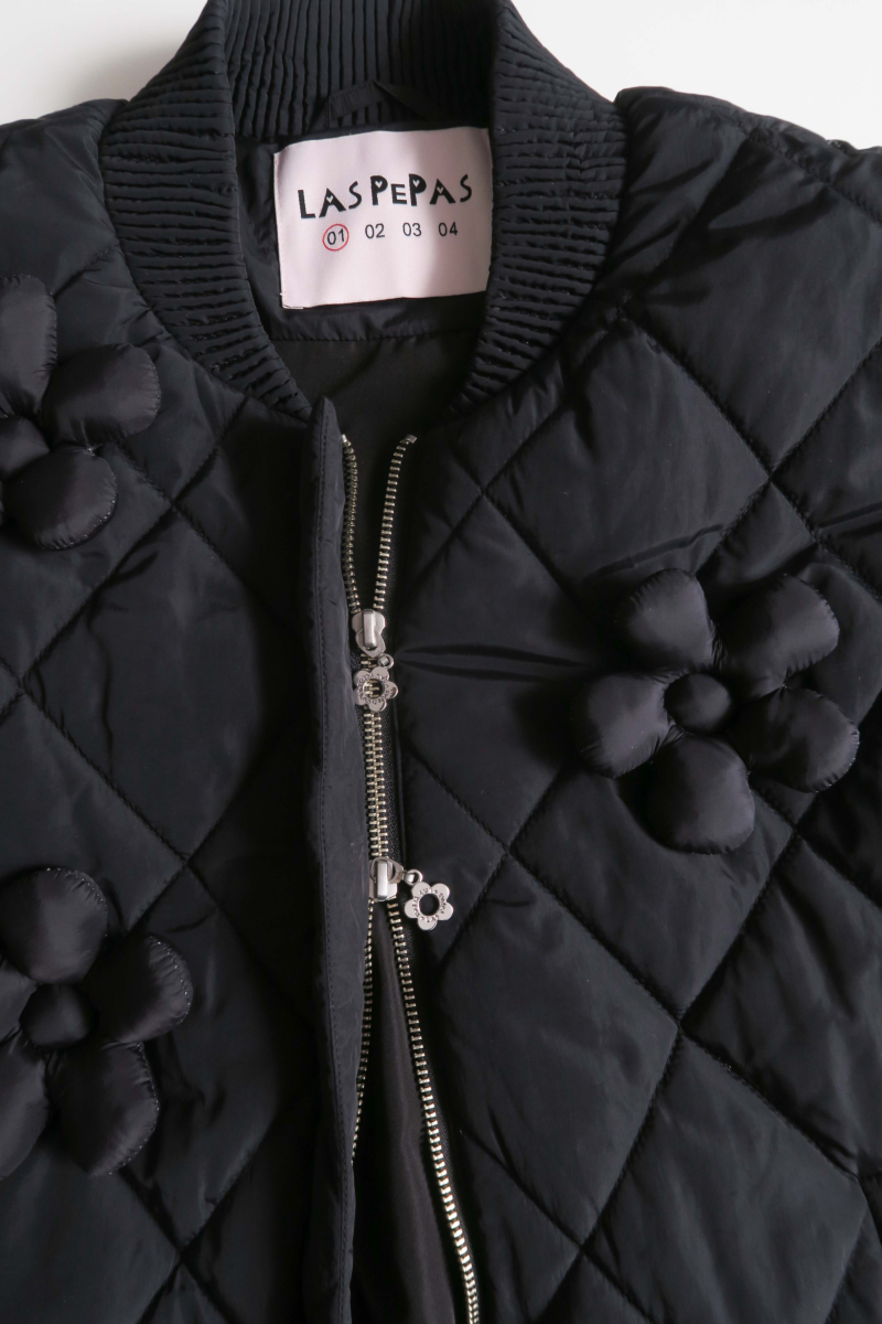 Campera matelaseada con apliques 3D de flores puffer, cuello y puños de ribb, cierre doble camino y mangas desmontables. 