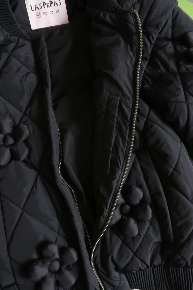 Campera matelaseada con apliques 3D de flores puffer, cuello y puños de ribb, cierre doble camino y mangas desmontables. 