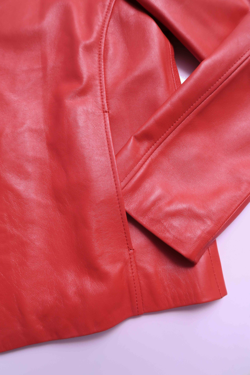 Campera de cuero rojo con cuello alto y cierre metálico, de calce recto y larga hasta la cadera.
