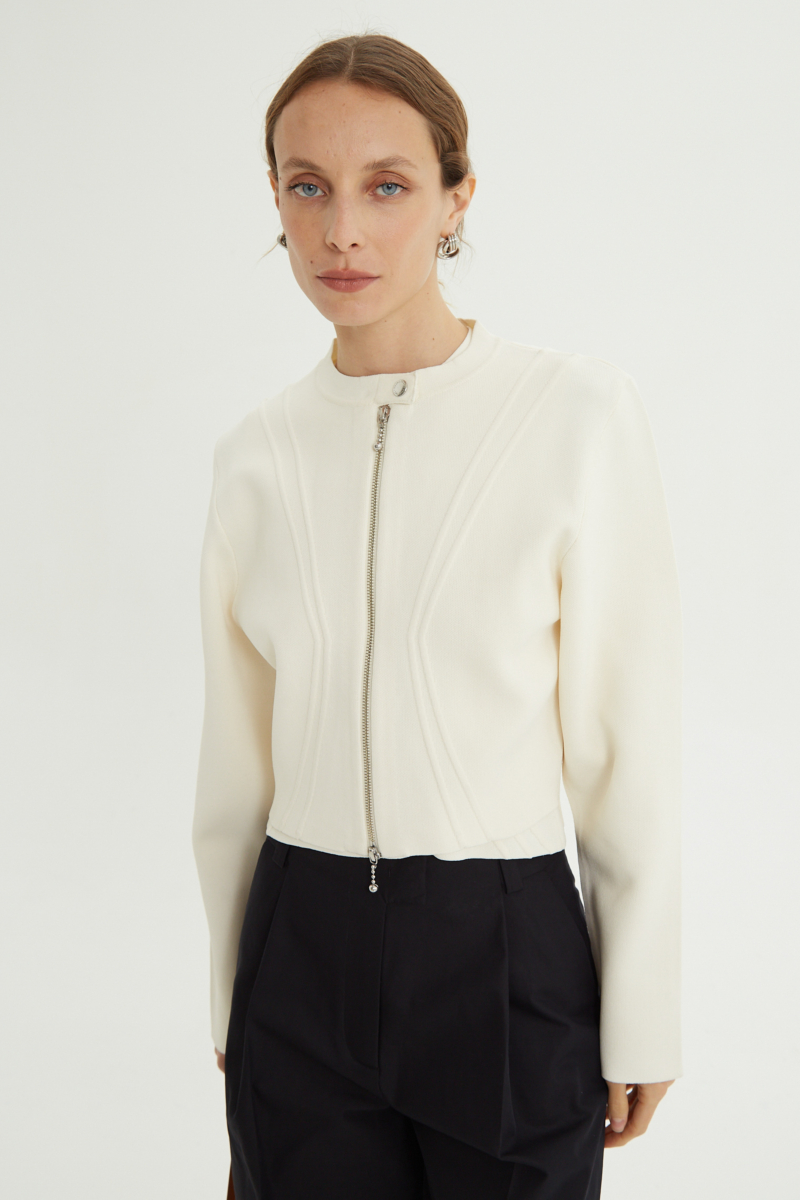 Campera crudo tejida estilo bomber larga a la cadera con cierre doble camino, cuello mao con broche snap, hombros anchos y terminación redondeada en el ruedo.