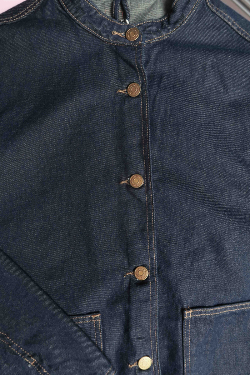 Campera de jean azul oscuro con costuras ocre, oversize, con cuello mao y bolsillos plaque. 
