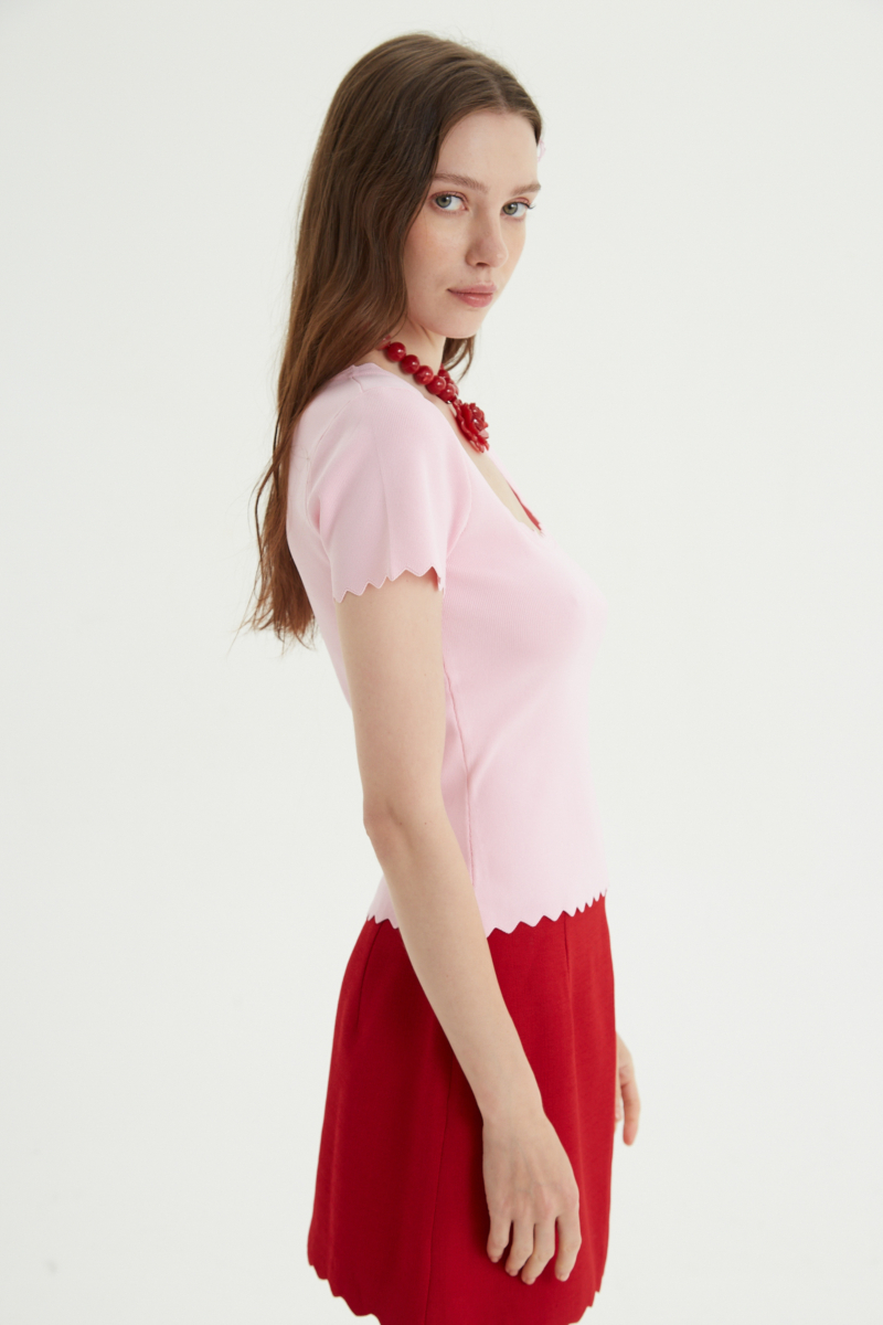 Remera rosa tejida  con terminación ondulada en mangas, ruedo y escote, de escote cuadrado y corte recto larga a la cadera. 
