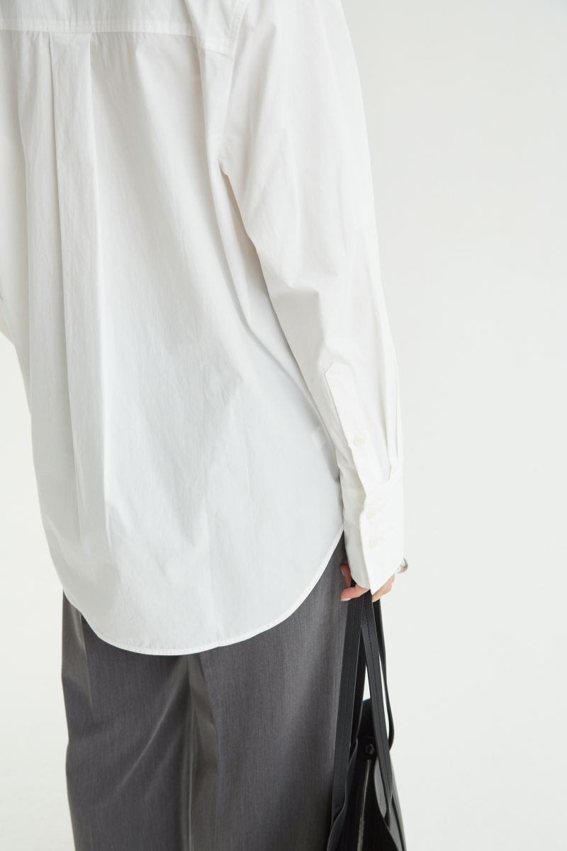 Camisa blanca oversize de poplín de algodón larga por debajo de la cadera con bolsillo aplicado al frente, tabla en la espalda y botones a tono.