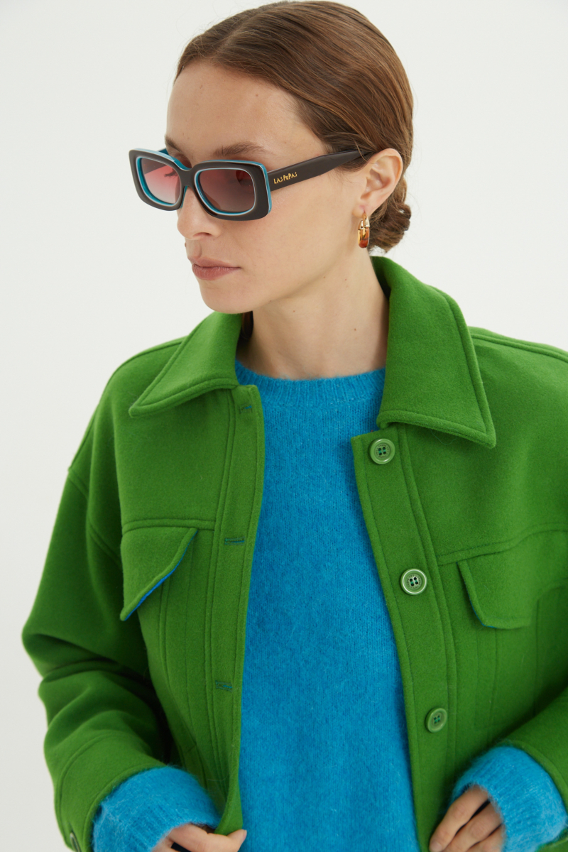 Campera verde de lana recta y larga hasta la cadera con sisas caídas, cuello en punta, botones a tono y bolsillos delanteros con solapa. 