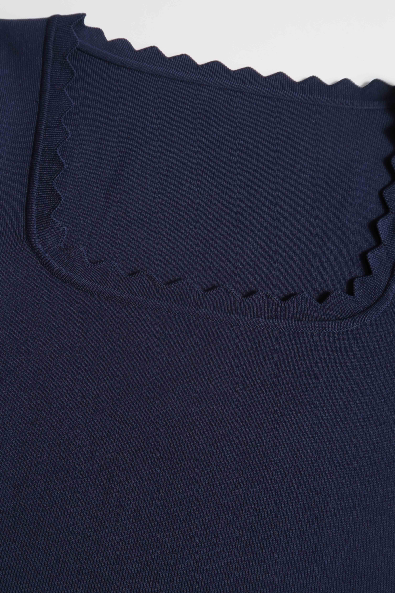 Remera azul tejida  con terminación ondulada en mangas, ruedo y escote, de escote cuadrado y corte recto larga a la cadera. 