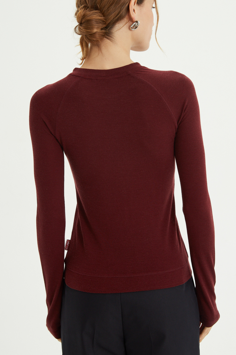 Remera bordo manga larga raglán de corte recto y larga a la cadera con cuello redondo y ruedo ancho. 
