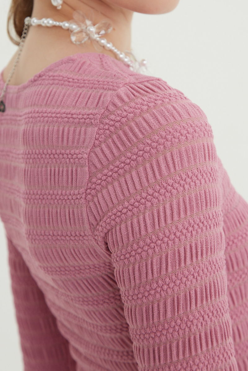 Remera rosa al cuerpo con mangas semi acampanadas, con escote a la base del cuello y textura fruncida. 
