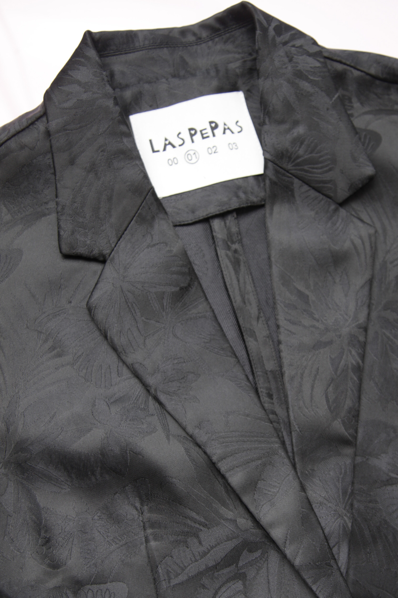 Saco negro sastrero recto de jacquard satinado con hombreras, solapa con cruce recto y botones tornasolados. 
