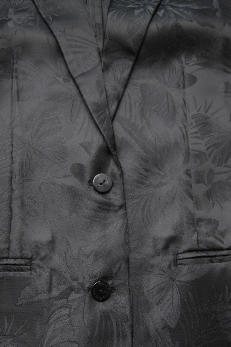 Saco negro sastrero recto de jacquard satinado con hombreras, solapa con cruce recto y botones tornasolados. 
