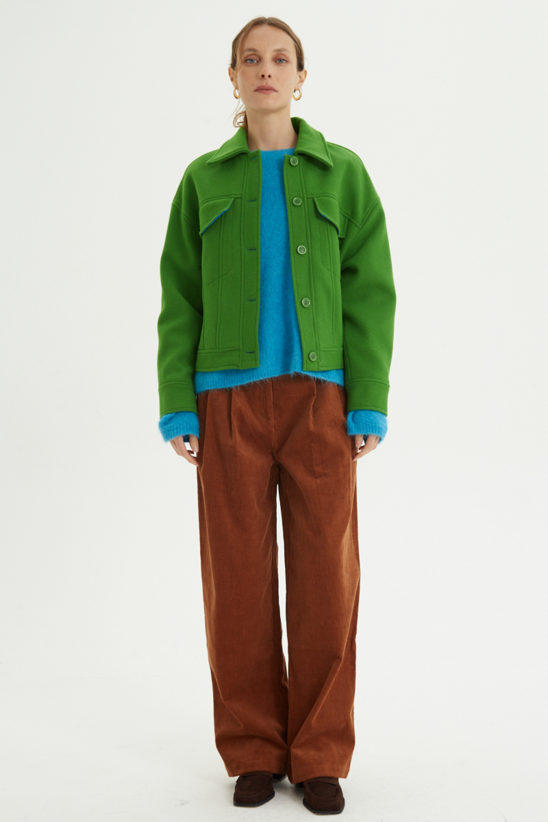 Campera verde de lana recta y larga hasta la cadera con sisas caídas, cuello en punta, botones a tono y bolsillos delanteros con solapa. 