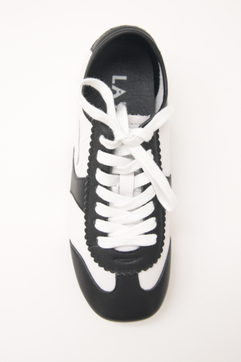 Zapatillas blanca y negra de cuero con recortes, punta cuadrada y suela de caucho.