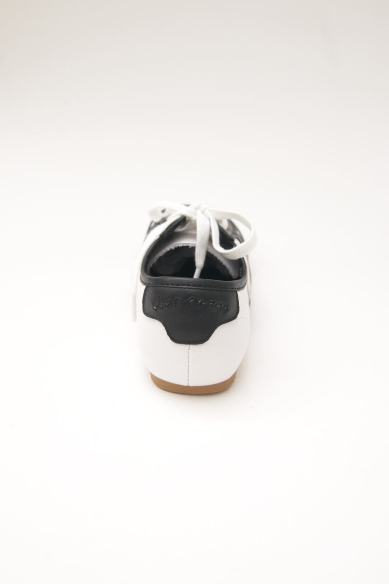 Zapatillas blanca y negra de cuero con recortes, punta cuadrada y suela de caucho.
