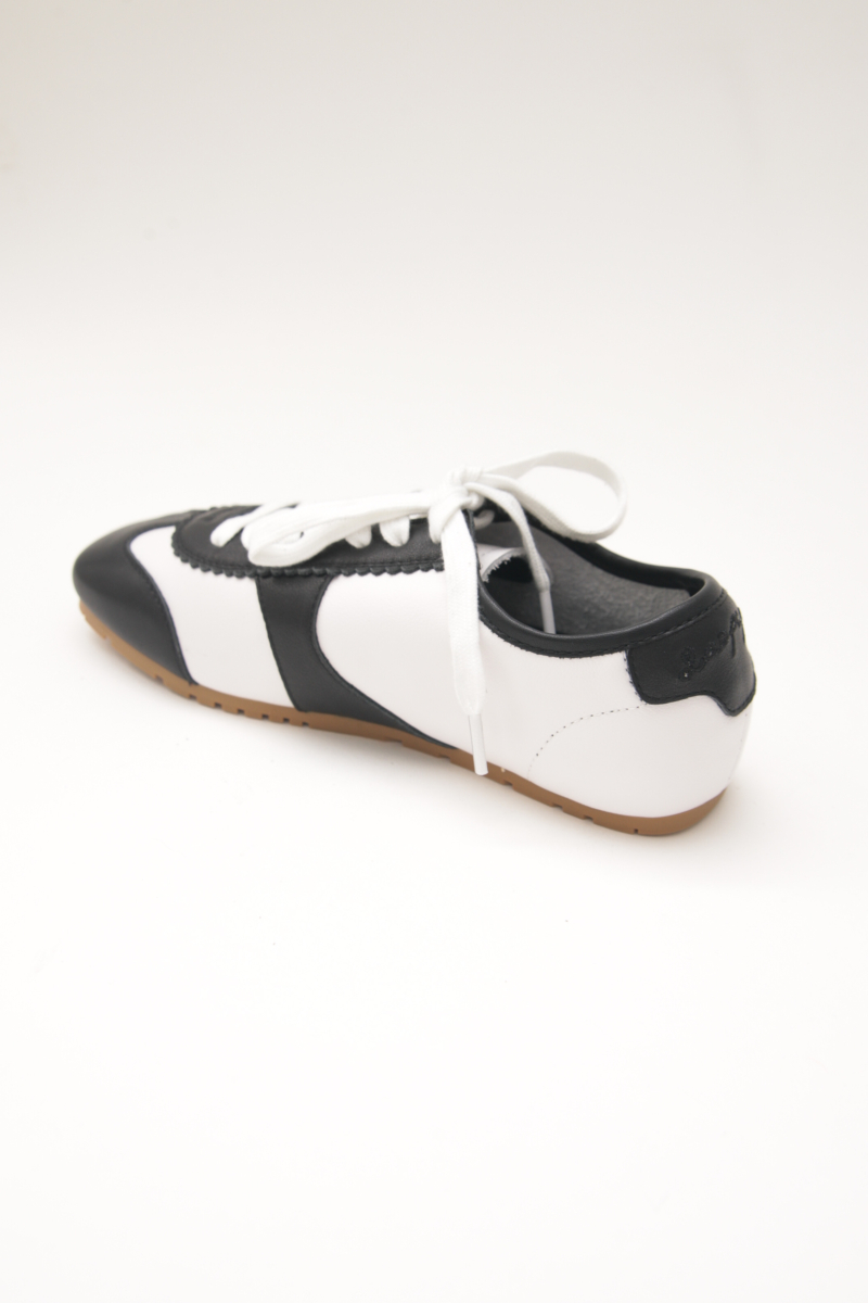 Zapatillas blanca y negra de cuero con recortes, punta cuadrada y suela de caucho.