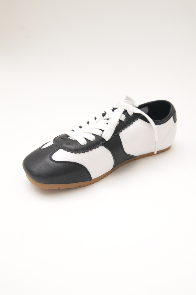 Zapatillas blanca y negra de cuero con recortes, punta cuadrada y suela de caucho.