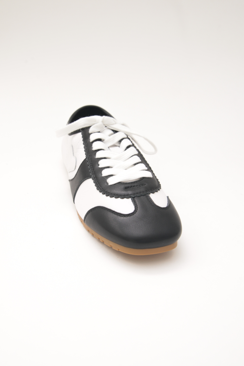 Zapatillas blanca y negra de cuero con recortes, punta cuadrada y suela de caucho.