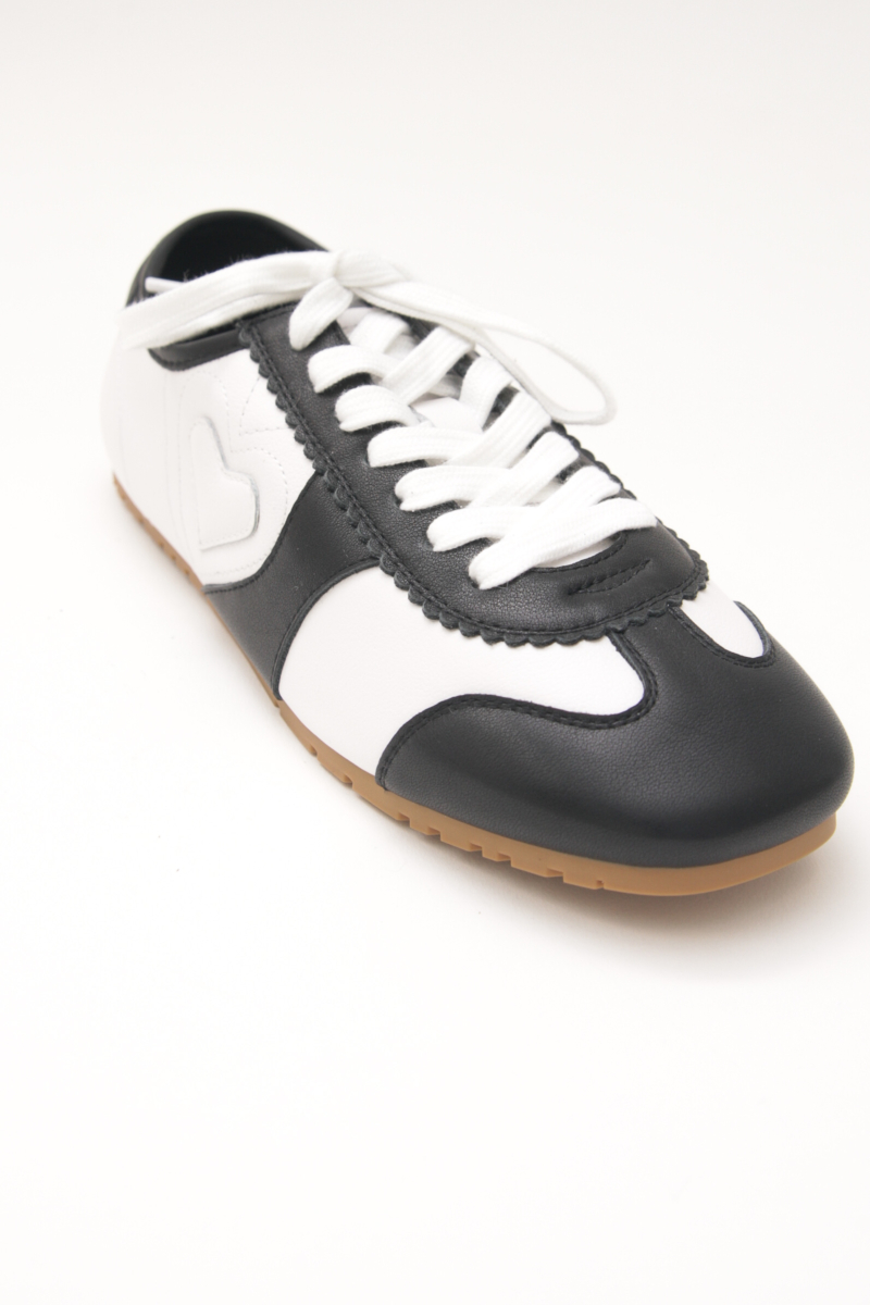 Zapatillas blanca y negra de cuero con recortes, punta cuadrada y suela de caucho.