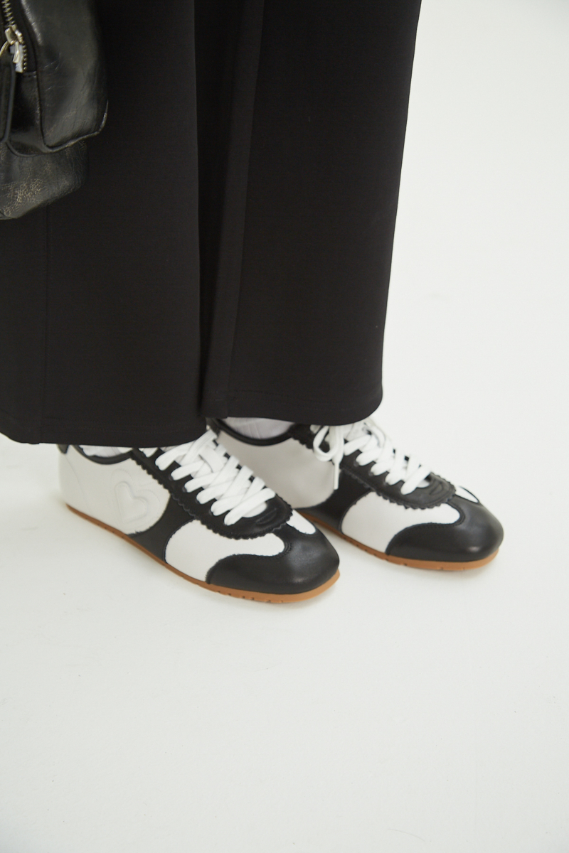 Zapatillas blanca y negra de cuero con recortes, punta cuadrada y suela de caucho.